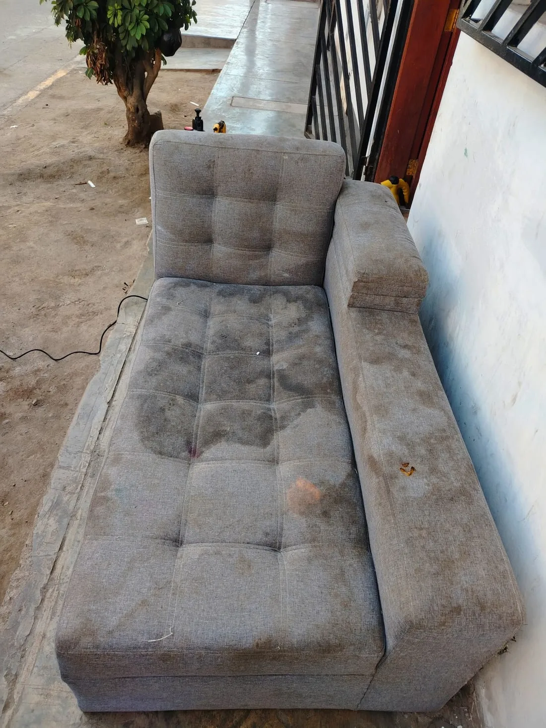 Chaise longue gris con manchas y suciedad antes del lavado