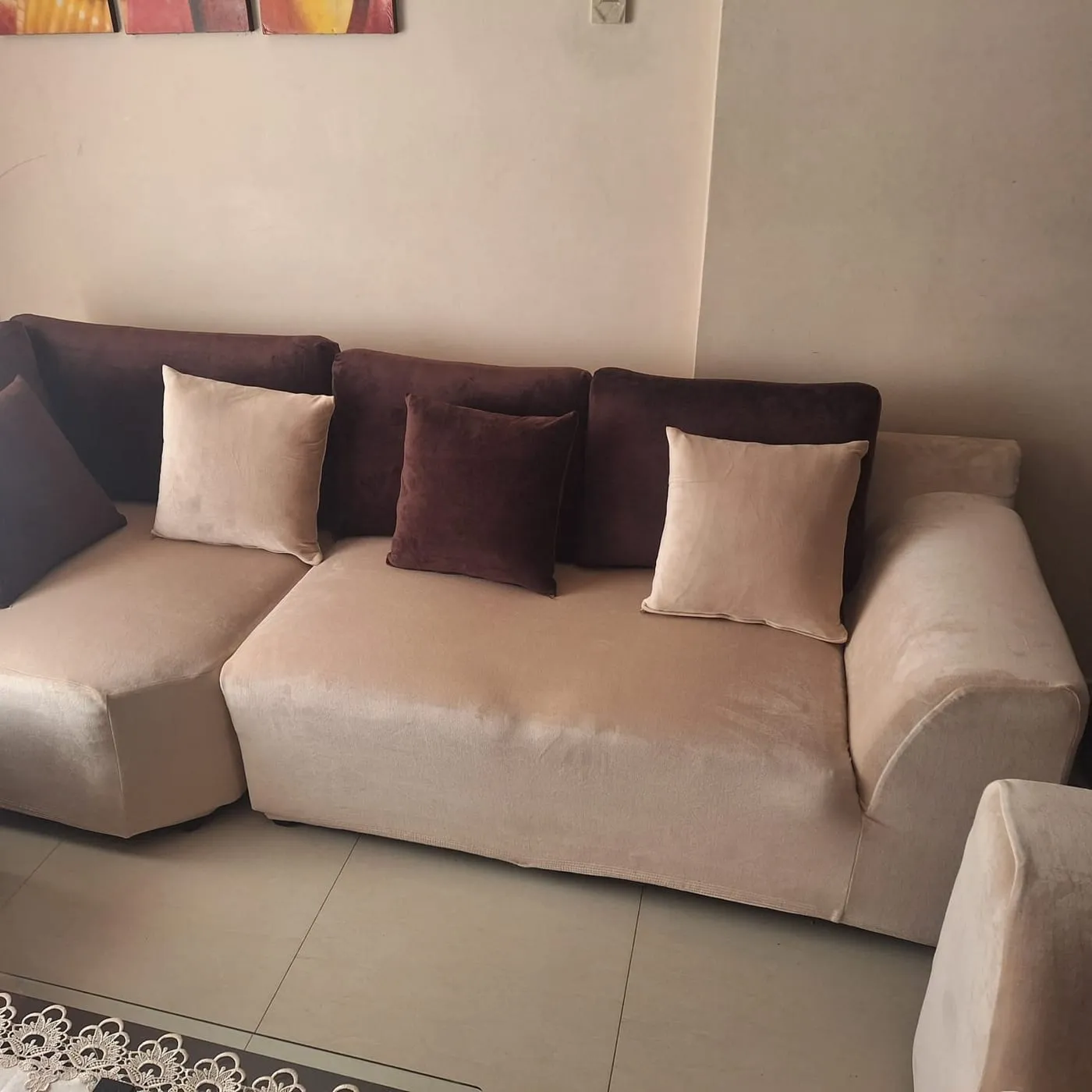 Sofá seccional en L protegido con funda beige y cojines a juego
